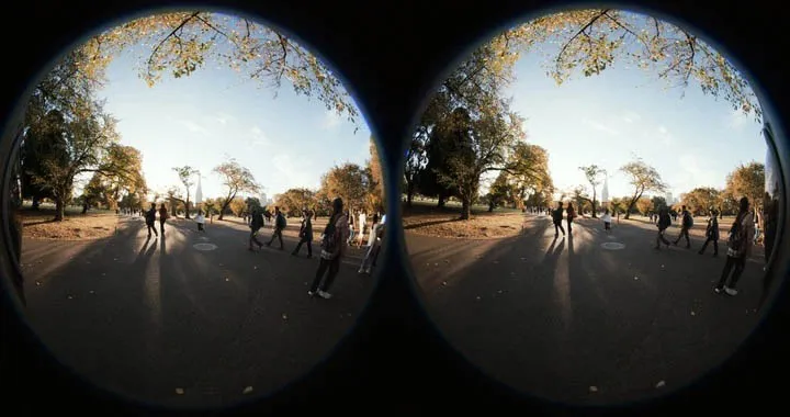 公園の舗装路を歩く人々を、二眼の魚眼レンズ視点で撮影した写真。夕方の柔らかい光が木々と人々を照らしている。