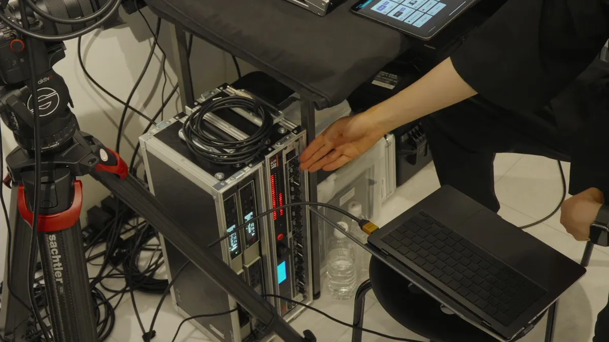 ハウリング抑制などに使用する音声処理機器を指しながら解説する様子。