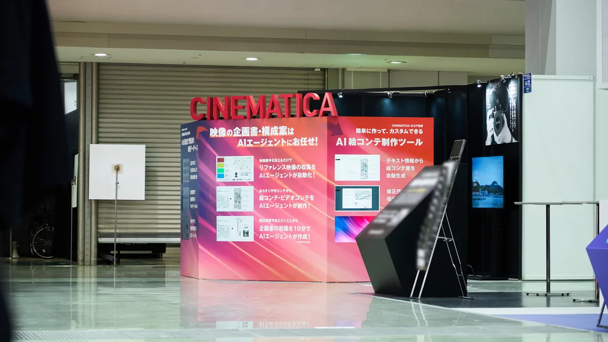 ブースから少し離れたところから見たブースの写真。赤色の CINEMATICA タワー が目立って見える。「映像の企画書・構成案はAIエージェントにお任せ！」および「AI絵コンテ制作ツール」という大きな見出しと、サイネージを活用した機能説明がされている。