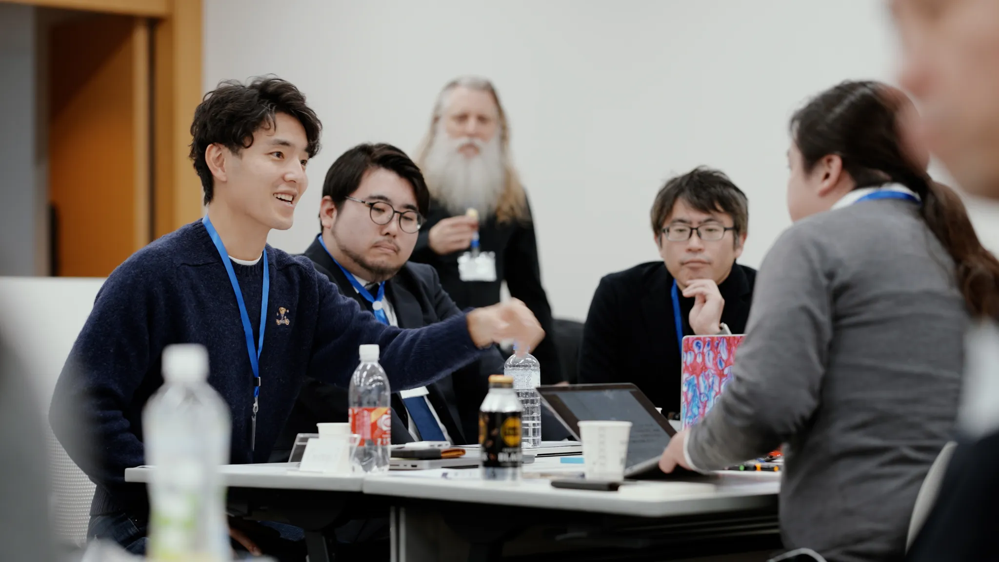 テーブルを囲んで談笑する参加者たち。一人が身振りを交えて話している。