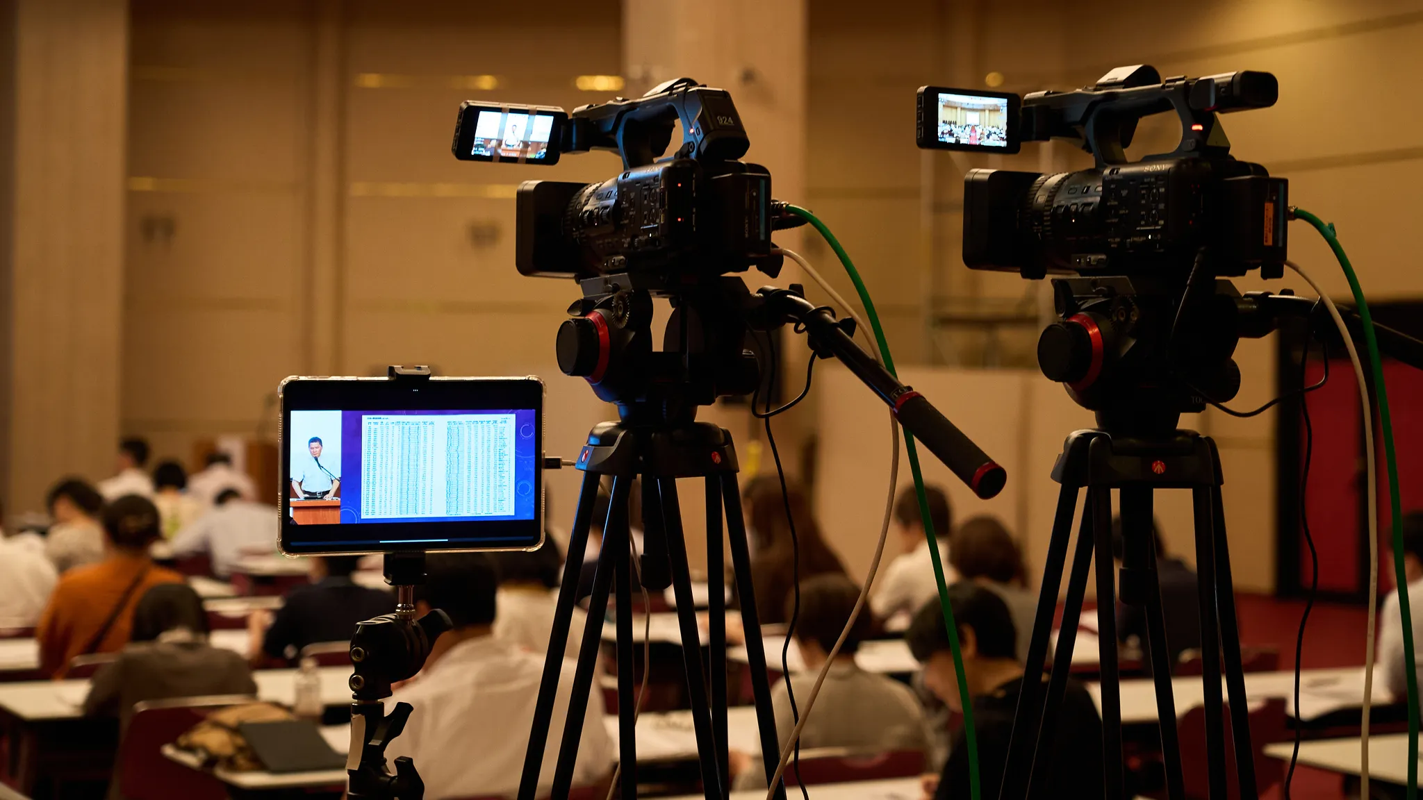 会場後方に設置された2台のビデオカメラと1台のタブレット。カメラは会場と発表者を撮影している。