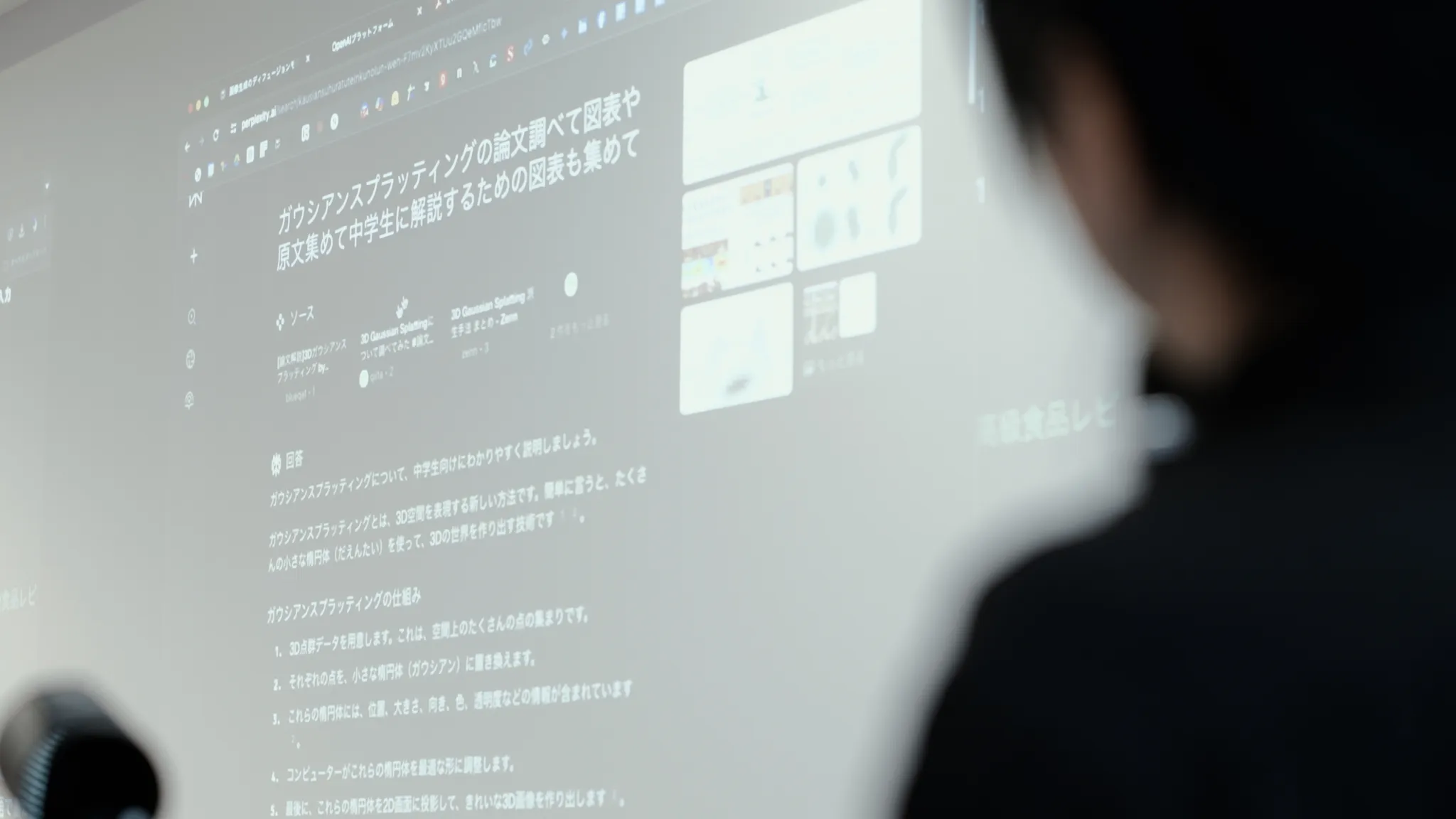 プロジェクターの画面を見つめる落合氏。画面には「ガウシアンスプラッティングの論文調べて図表や原文集めて中学生に解説するための図表も集めて」とAIに送信された画面。