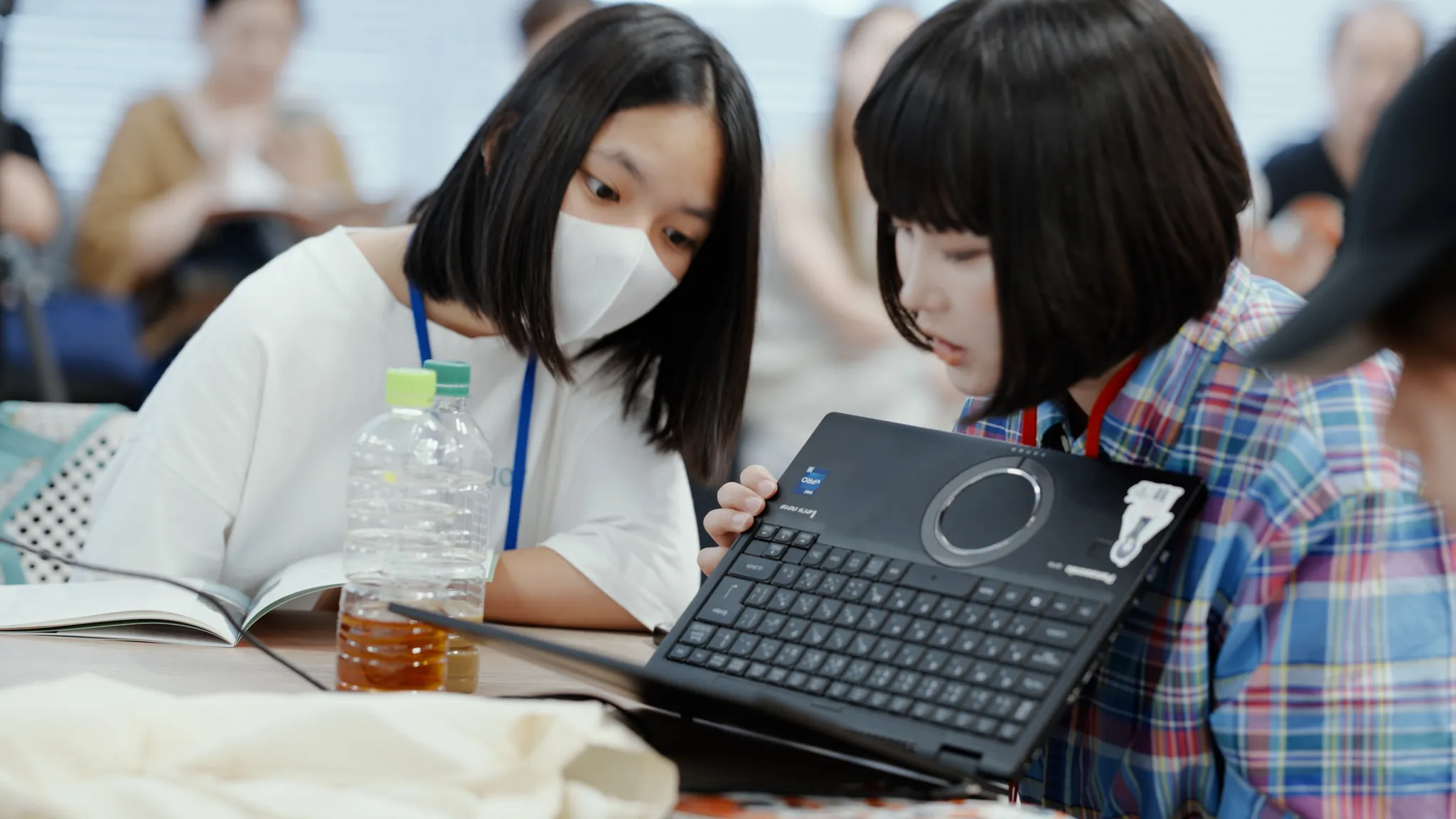 机に向かい、2人でノートパソコンの画面をのぞき込む子どもとティーチングアシスタントのKYUN_KUN。