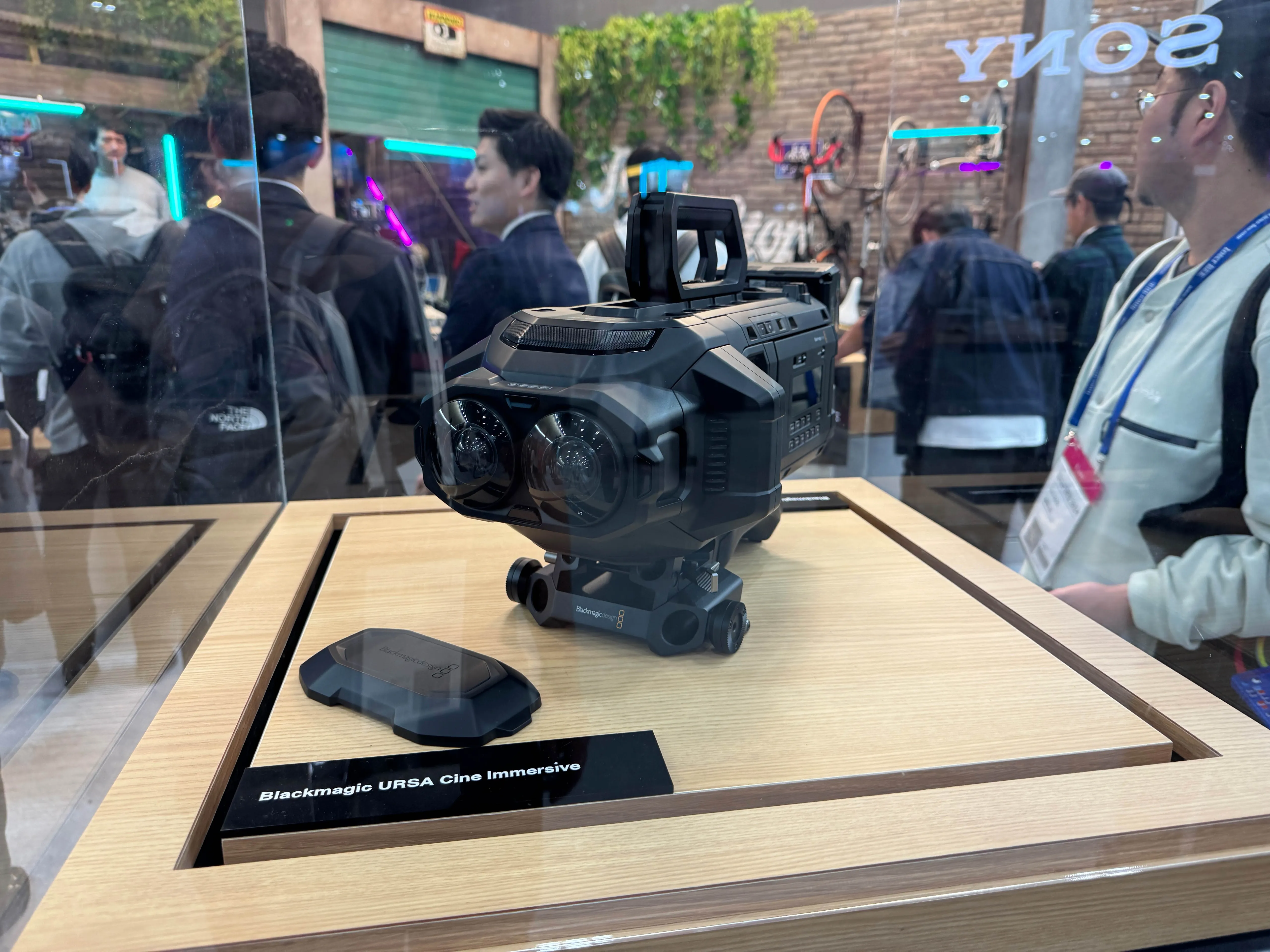 ガラスケースに展示されたBlackmagic URSA Cine Immersiveカメラの写真。前面に左右2つのレンズが搭載され、立体視撮影に対応している様子。