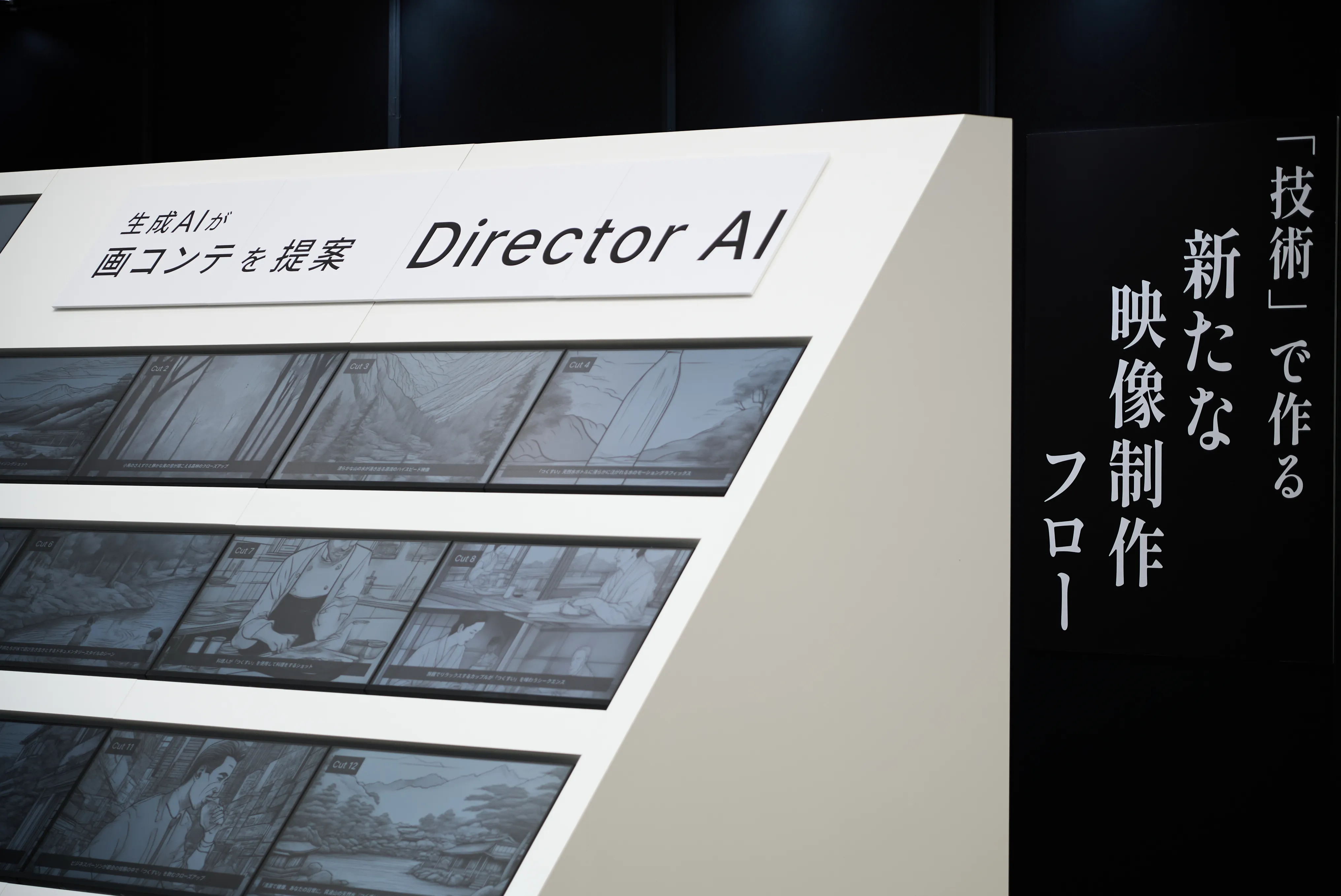 展示什器のクローズアップ写真。白い台形の什器の角あたりがクローズアップされている。文字「生成AIが画コンテを提案 Director AI」ディスプレイが複数枚埋め込まれており、画面に生成された絵が表示されている。什器後ろの壁に文字「技術で作る新たな映像制作フロー」